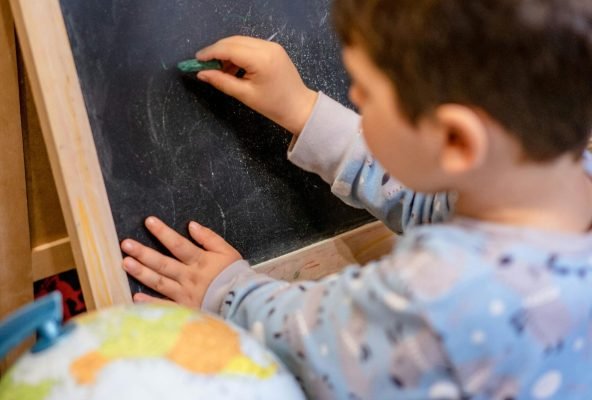 A child exploring home education using a blackboard and chalk, fostering early learning.